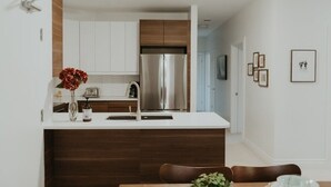 Een moderne keuken met witte kasten, een roestvrijstalen koelkast en een houten keukeneiland.