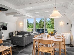 Un espacio de estar moderno con sofá, mesa de comedor, sillas y televisor.
