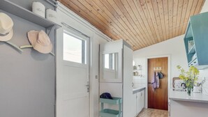 Une cuisine moderne avec un plafond en bois, une porte blanche et un petit chariot.