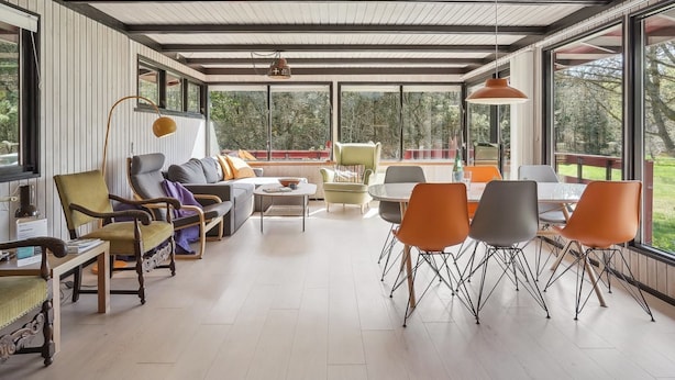 Amplia sala de estar con techo alto, ventanas grandes y una combinación de muebles modernos y clásicos.