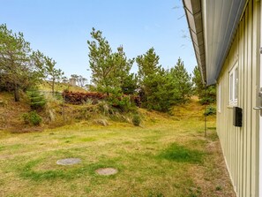 Une cour verdoyante avec des arbres, un bâtiment et un couvercle de regard d’égout.