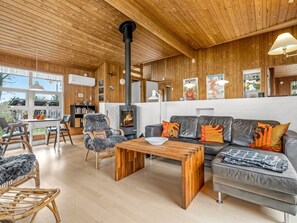 Un salon chaleureux avec une cheminée, des meubles en bois et un canapé agrémenté de coussins colorés.