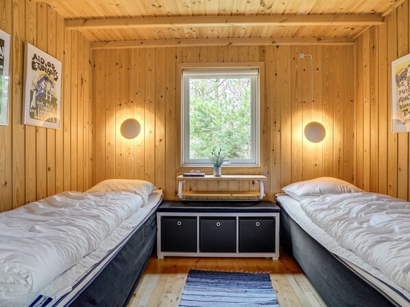 Une cabine avec deux lits, une fenêtre donnant sur la forêt et des lampes fixées au mur.