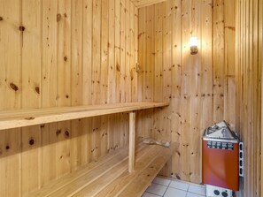 L’intérieur d’une cabane en bois, avec une étagère en bois, un radiateur et un luminaire fixé au mur.