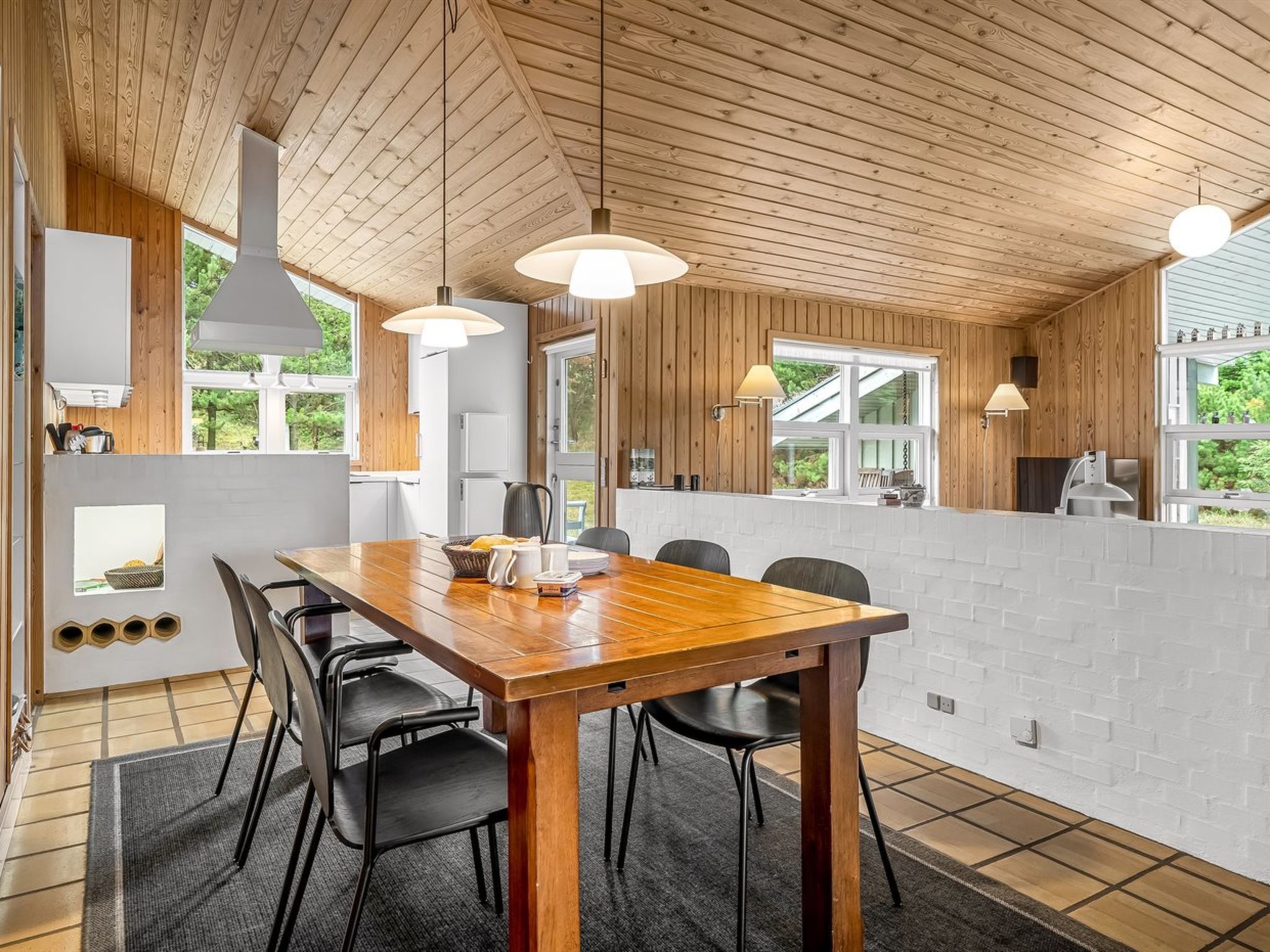 Une cuisine moderne avec des poutres en bois au plafond, une grande table à manger et des chaises noires.