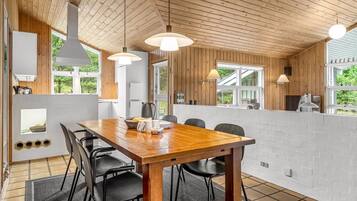 Une cuisine moderne avec des poutres en bois au plafond, une grande table à manger et des chaises noires.