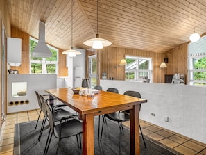 Una cocina moderna con vigas de madera en el techo, una gran mesa de comedor y sillas negras.