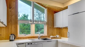 Eine moderne Küche mit Holzwänden, einem großen Fenster und Edelstahlgeräten.