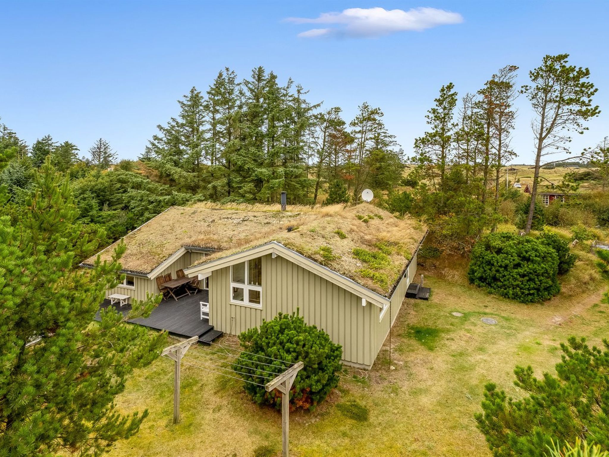 Une maison de plain-pied, dotée d’un toit en pente, entourée d’une forêt dense.