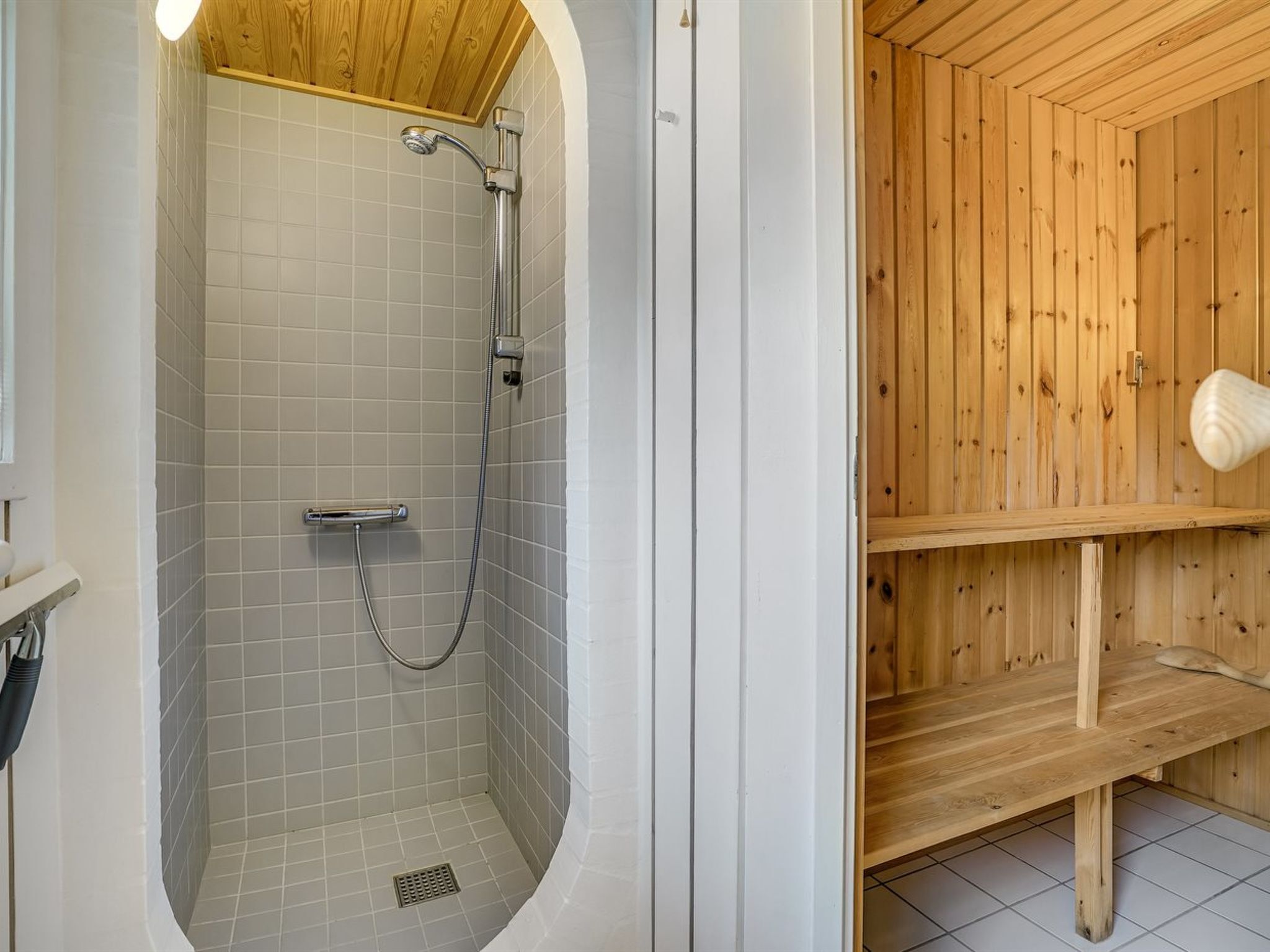 Une salle de bain avec une douche, des murs carrelés et un banc en bois.