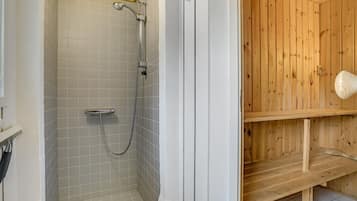 Une salle de bain avec une douche, des murs carrelés et un banc en bois.