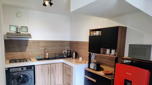 Une cuisine compacte équipée d’un lave-linge, d’une machine à café et d’un grille-pain.