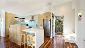 A modern kitchen with wooden cabinets, a central island, and a stainless steel refrigerator. - Tri level house with 5 bdrms, game room, balcony with valley view & deck. (Rye)