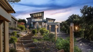 A modern house with a stone pathway leading to the entrance, surrounded by greenery. - Tri level house with 5 bdrms, game room, balcony with valley view & deck. (Rye)