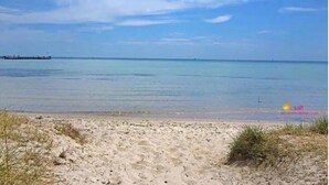 A beach with clear water, a pier in the distance, and sparse vegetation. - Tri level house with 5 bdrms, game room, balcony with valley view & deck. (Rye)