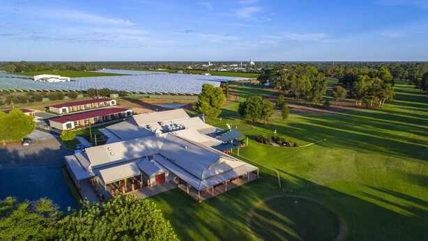 An aerial view of a large building complex with multiple structures, surrounded by green fields and trees.