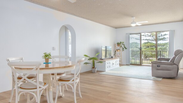 Un salon spacieux comprenant un coin repas, un ventilateur de plafond, une grande fenêtre offrant une belle vue et un balcon.