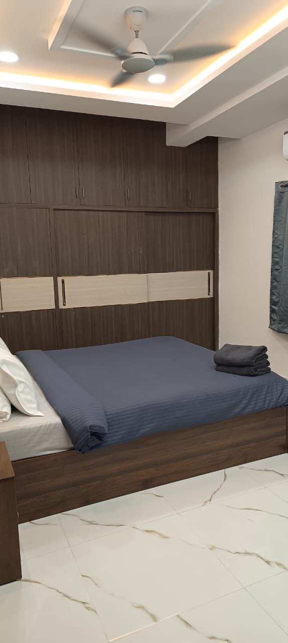 Un dormitorio con cama, cabecera de madera, ventilador de techo y suelo de mármol blanco.