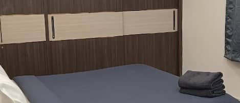 Un dormitorio con cama, cabecera de madera, ventilador de techo y suelo de mármol blanco.