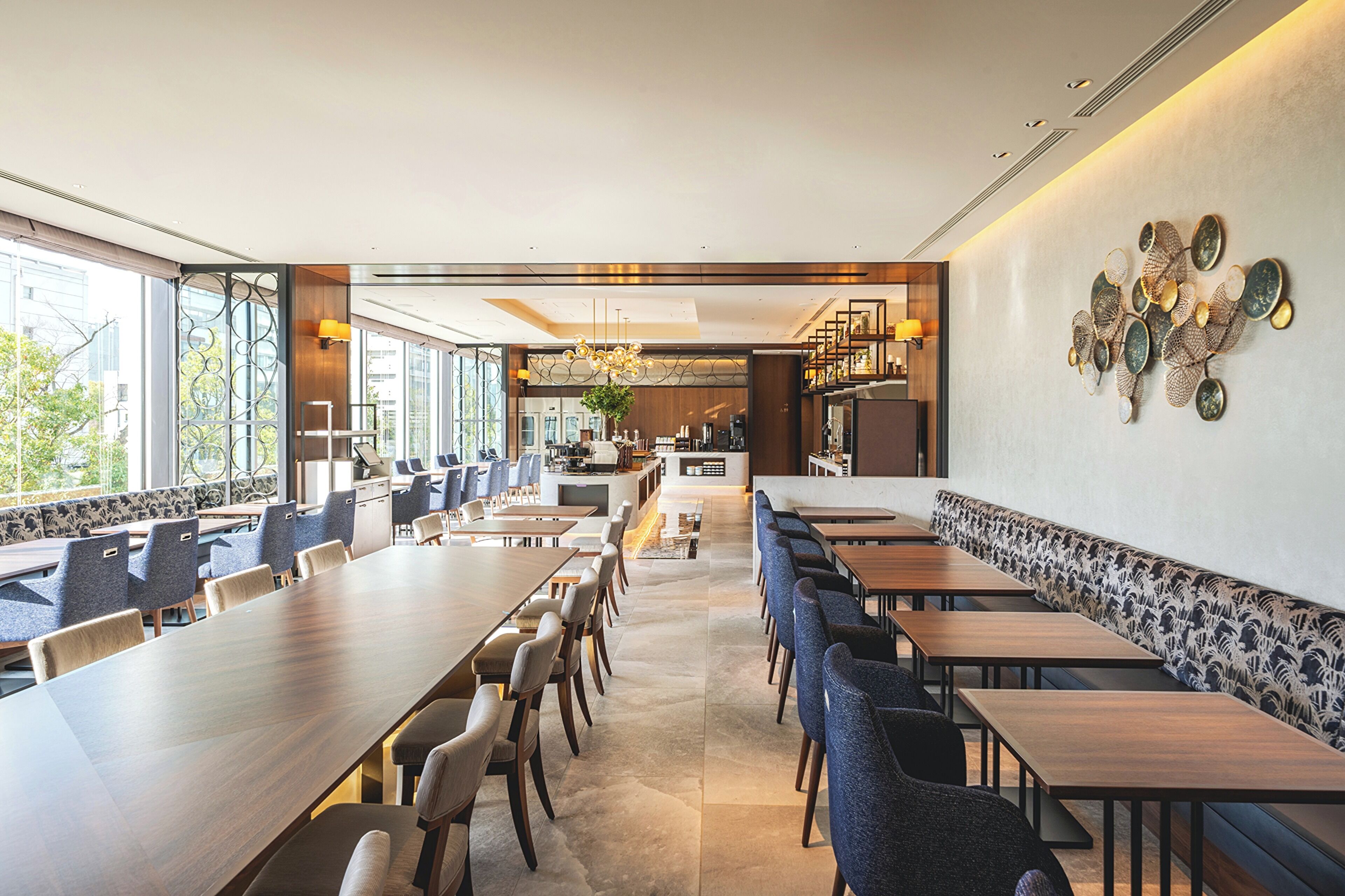 Een modern restaurantinterieur met lange gedeelde tafels, afzonderlijke zitjes en een bar.
