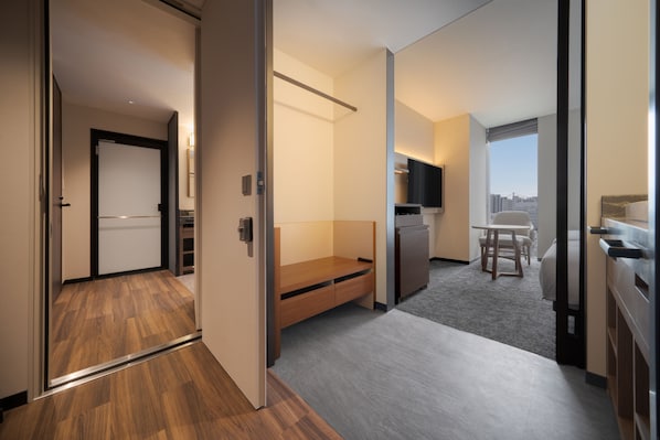 A modern hotel room with a wooden floor, a bed, a desk, a chair, a small kitchenette, and a large window offering a city view. - Premier Hotel-CABIN PRESIDENT-Tokyo (Tokyo)