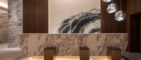 A reception area with a marble counter, wooden panels, and hanging pendant lights.
