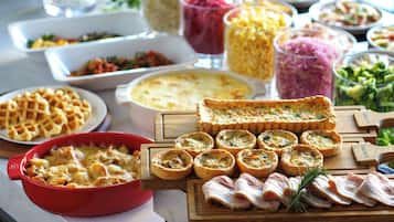 A buffet table with various dishes including waffles, quiches, and a selection of meats.