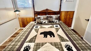 Un dormitorio con cabecera de madera, colcha estampada con motivos de animales y ventana con persianas.