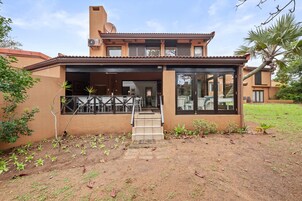 A two-story house with a covered patio, a satellite dish, and a small garden area.
