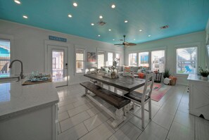 A spacious kitchen with a large island, white cabinetry, and a ceiling fan.