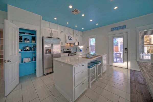 A kitchen with white cabinets, a central island, and a blue accent wall.