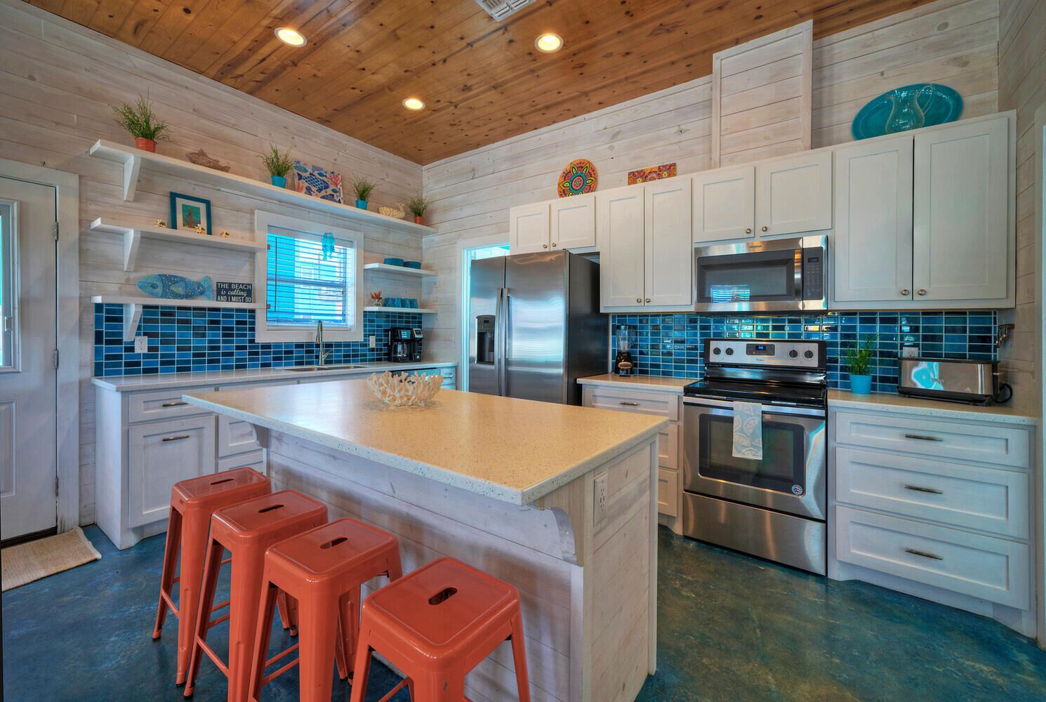A modern kitchen with white cabinets, stainless steel appliances, and a central island with bar stools.