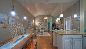Una cocina amplia con armarios blancos, encimera de granito y un comedor con banco y mesa de madera.