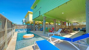 A pool area with lounge chairs, a floating ring, and a covered patio. - Near the Beach, Private Pool w/ Free Heat, Firepit | Laid Back Lime by AvantStay (Port Aransas)