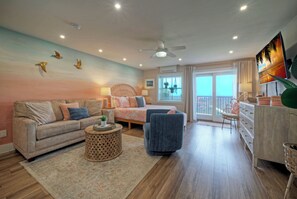 A living room with a sofa, armchair, coffee table, and a TV mounted on the wall. - Ocean View w/ Pool, Tennis/Pickleball, Beach Access | Summer Love by AvantStay (Port Aransas)