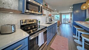 Une cuisine moderne avec des meubles bleus, des appareils en acier inoxydable et un grand îlot central doté de tabourets.