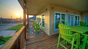 A wooden deck with outdoor seating and a view of the sunset.