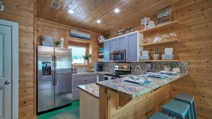 Une cuisine de style rustique, avec des éléments en bois, un îlot central, des appareils en acier inoxydable et des tabourets de bar.