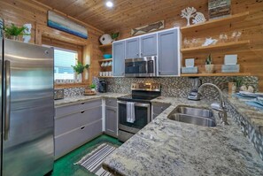 Eine Küche mit Granit Arbeitsplatten, Edelstahlgeräten und Holzschränken.