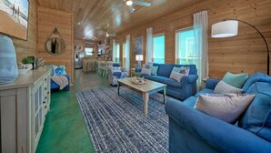 Un intérieur en bois avec un canapé bleu, une table basse et un ventilateur de plafond.