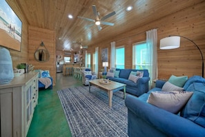 A wooden interior with a blue sofa, a coffee table, and a ceiling fan.