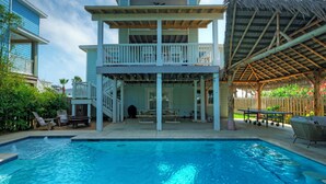 A two-story building with a pool, outdoor seating, and a covered area.