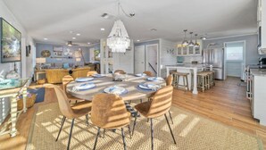 A spacious dining area with a round table set for six, surrounded by six chairs.