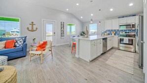 A modern kitchen with white cabinets, a stainless steel refrigerator, and a built-in oven. - Priv Pool, Covered Patio Lounge w/ Bar, Sunset Views | Green Gecko by AvantStay (Port Aransas)