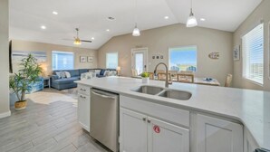 A modern kitchen with a central island, built-in dishwasher, and a dining area with a table and chairs.