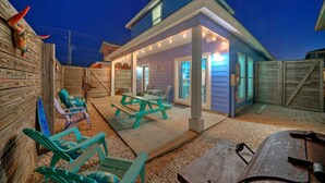 A two-story house with a covered patio, outdoor seating, and a wooden fence.