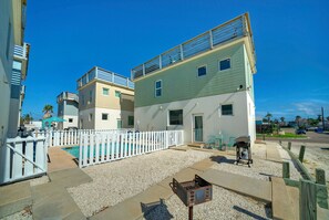 Edificio residencial con piscina, cerca de piquetes blancos y una parrilla.
