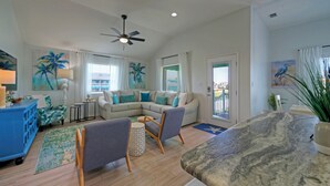 A spacious living room with a sectional sofa, a blue armchair, a small round table, and a ceiling fan.