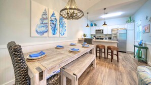Un espace repas avec une table en bois, des bancs et un lustre.