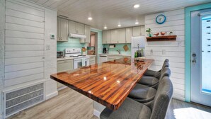 A kitchen with a central island, white cabinetry, and a teal accent wall. - Big Yard w/ Priv Pool, Firepit, Patio | Near the Beach | Reel Time by AvantStay (Port Aransas)